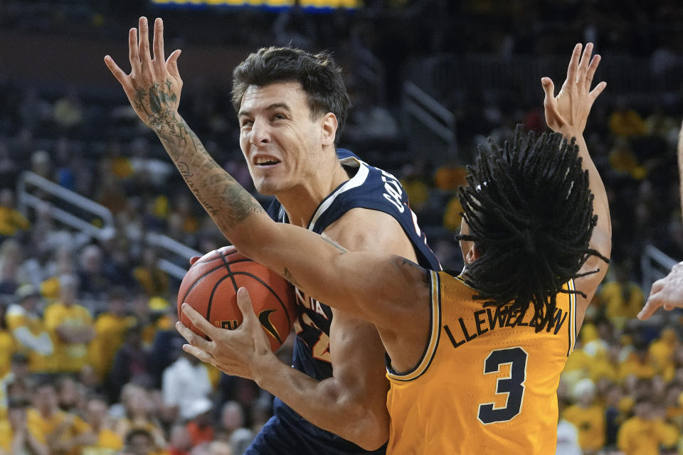 Virginia center Francisco Caffaro (22) charges into Michigan guard Jaelin Llewellyn (3) in the first half of an NCAA college basketball game in Ann Arbor, Mich., Tuesday, Nov. 29, 2022. (AP Photo/Paul Sancya)