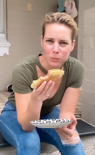 Belinda Russell sitting on a step eating a toastie