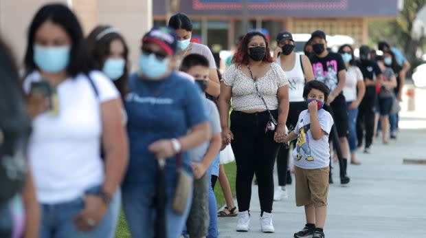 People waiting in line outside a Covid testing site wearing masks