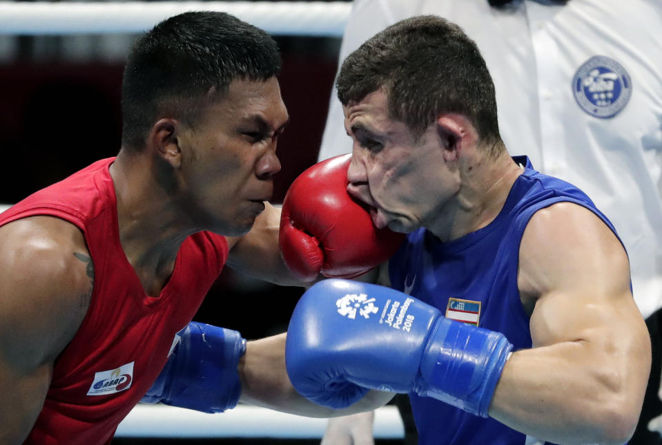FILE - In this Aug. 31, 2018, file photo, Phillippines' Eumir Felix Marcial, left, and Uzbekistan's Israil Madrimov fight in their men's middleweight boxing semifinal at the 18th Asian Games in Jakarta, Indonesia. Professional boxers will fight at the Olympics this month for the second time following a century of exclusively amateur competition in the sport. More than 40 fighters with pro experience are listed in the Tokyo Olympic field, a sharp increase from just three pros in Rio de Janeiro. (AP Photo/Lee Jin-man, File)