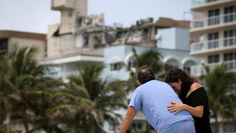 Dos personas frente a la torre colapsada