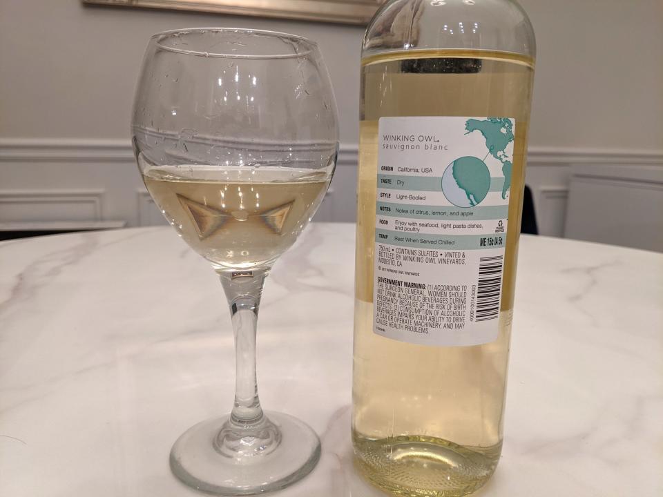 A bottle of white winking owl wine from Aldi and a glass of it