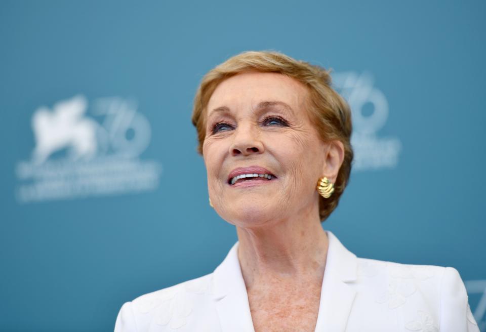 Julie Andrews is photographed in a white suit, paired with gold stud earrings