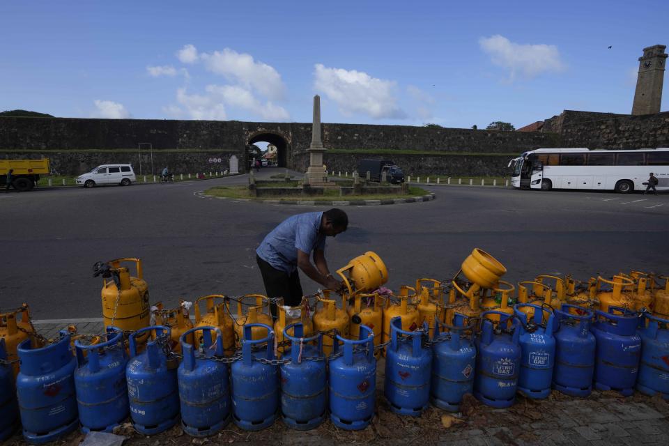 A man uses a padlock to secure his empty cooking gas canister placed in a queue expecting government supply in Galle, Sri Lanka, Tuesday, June 28, 2022. (AP Photo/Eranga Jayawardena)