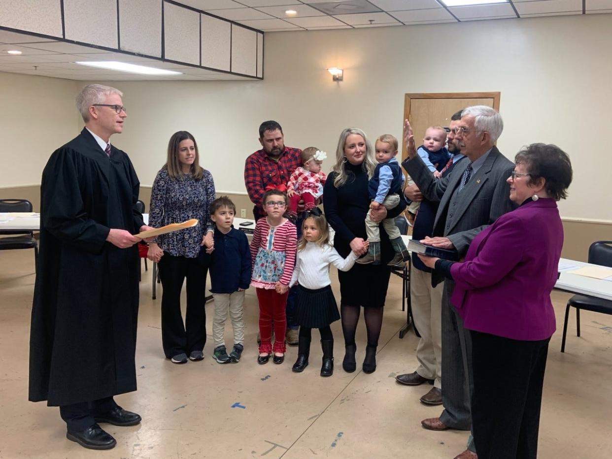 Newly elected Madison County Commissioner Bill Briggs is sworn into office by 24th District Court Judge Matt Rupp while his family looks on.