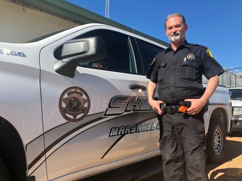 Marshall County Deputy Sheriff Steve Beebe stands next to a police car in Madill, Oklahoma