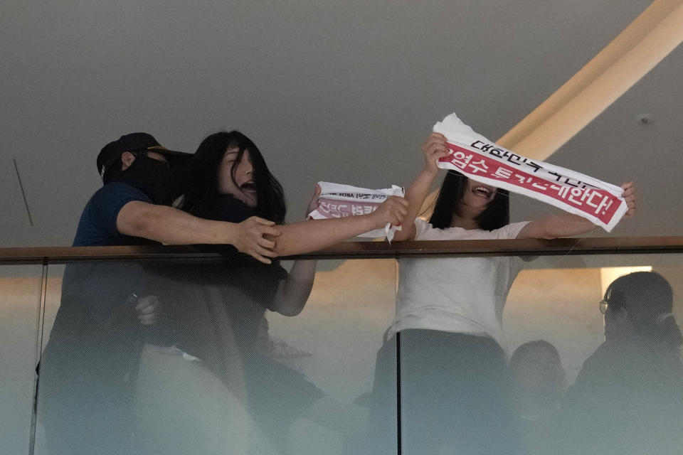 South Korean students are detained by police officers as they attempt to enter to Japanese Embassy to protest denouncing to release treated radioactive water into the sea from the damaged Fukushima nuclear power plant, at a building which houses Japanese Embassy, in Seoul, South Korea, Thursday, Aug. 24, 2023. The operator of the tsunami-wrecked Fukushima Daiichi nuclear power plant says it has begun releasing its first batch of treated radioactive water into the Pacific Ocean — a controversial step, but a milestone for Japan's battle with the growing radioactive water stockpile. The letters read "Oppose to release radioactive water." (AP Photo/Lee Jin-man)