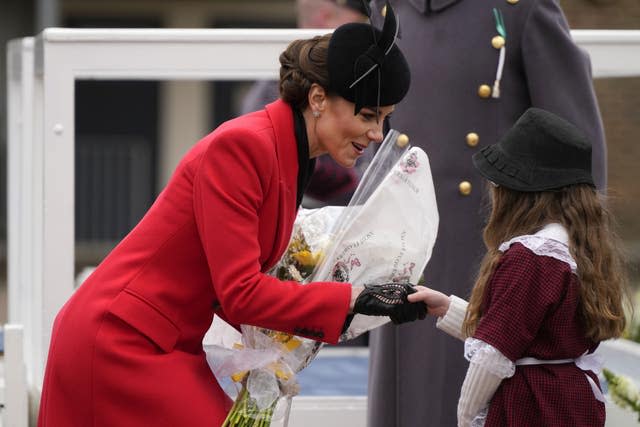 Kate bekommt von einem jungen Mädchen in traditioneller walisischer Tracht Blumen überreicht 