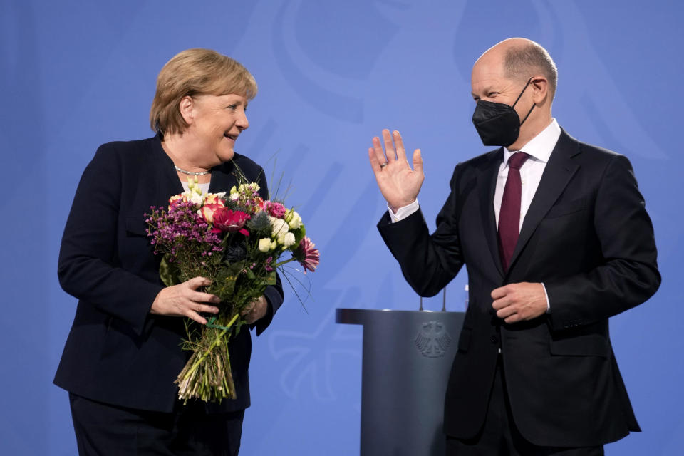 New elected German Chancellor Olaf Scholz, right, gives flowers to former Chancellor Angela Merkel during a handover ceremony in the chancellery in Berlin, December 8, 2021. / Credit: Markus Schreiber/AP