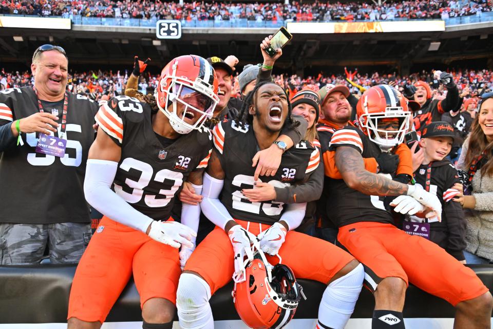 Ronnie Hickman #33, Martin Emerson Jr. #23, and Greg Newsome II #0 of the Cleveland Browns celebrate with fans after beating the Pittsburgh Steelers 13-10 at Cleveland Browns Stadium on November 19, 2023 in Cleveland, Ohio.