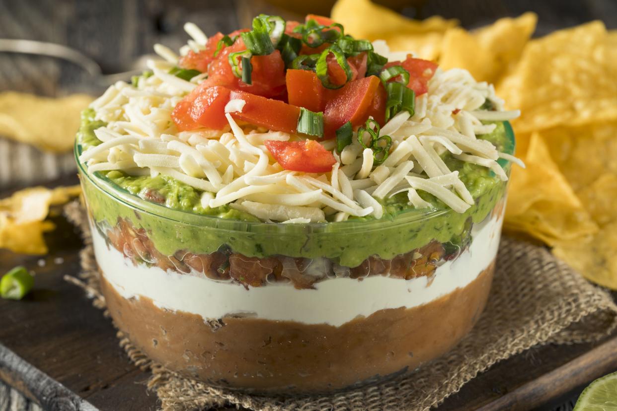 Focus on 7 layer dip on napkin with blurred tortilla chips in the background