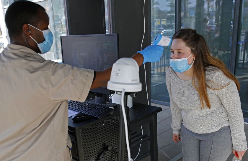 A security guard double checks a customer after she was screened by a body temperature screening device, before entering an IKEA outlet in the Israeli coastal town of Netanya on April 22, 2020, after authorities eased down some of the measures that have been in place during the novel conronavirus pandemic crisis. (Photo by JACK GUEZ / AFP) (Photo by JACK GUEZ/AFP via Getty Images)