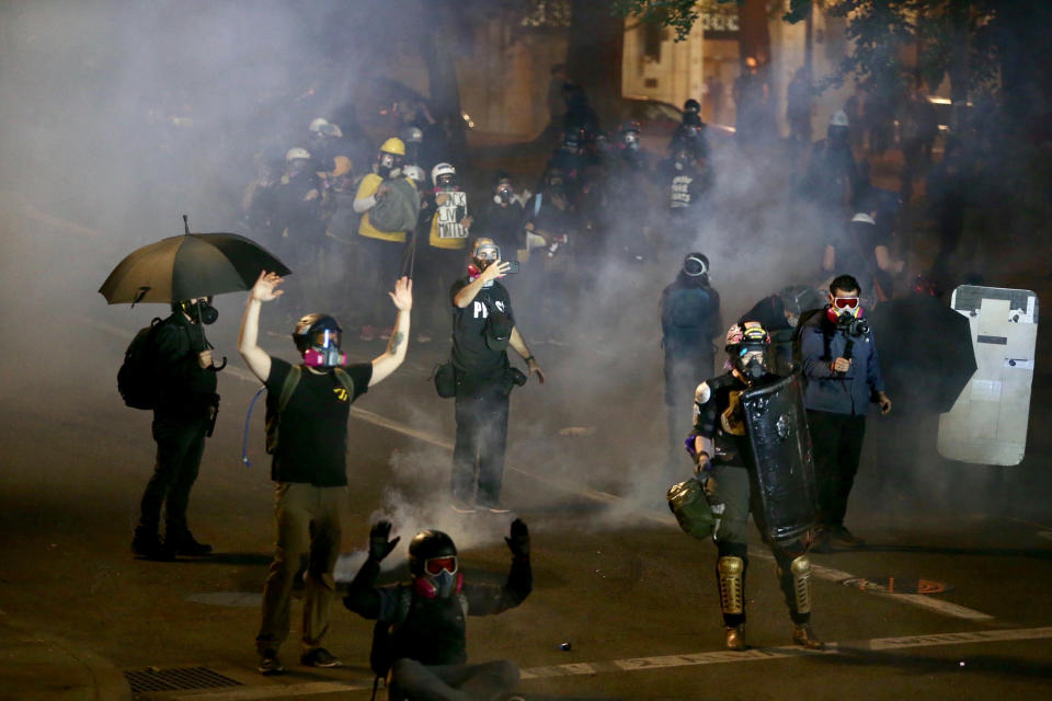 Portland protests return downtown as police use tear gas early Thursday, Aug. 13, 2020. Protesters and police clashed in downtown Portland in a demonstration that lasted into the predawn hours of Thursday, with some in the crowd setting a fire and exploding commercial grade fireworks outside a federal courthouse that's been a target in months of conflict for Oregon's largest city. (Sean Meagher/The Oregonian via AP)