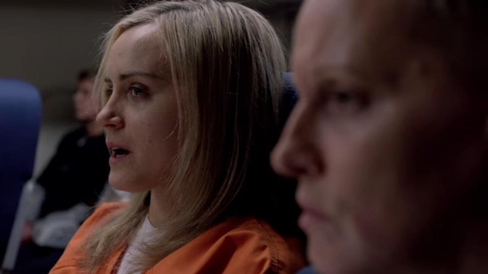 Piper sitting in an airplane in orange overalls