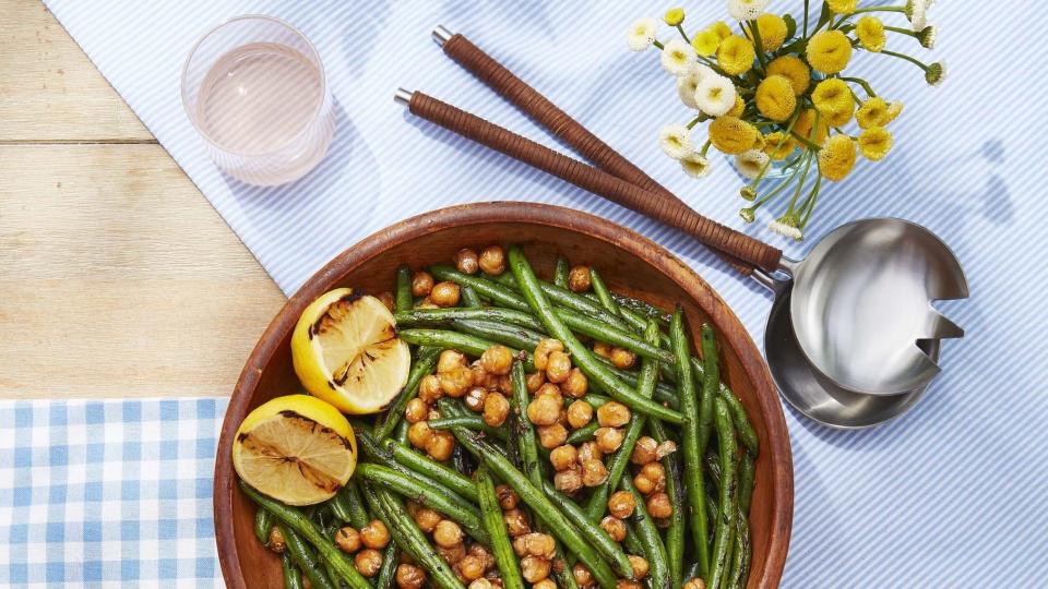 green beans with crispy chickpeas in a wooden bowl with two grilled lemon halves