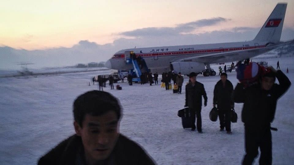 Passengers walk across the snowy tarmac at Pyongyang's airport. Photo: AP Photo/David Guttenfelder