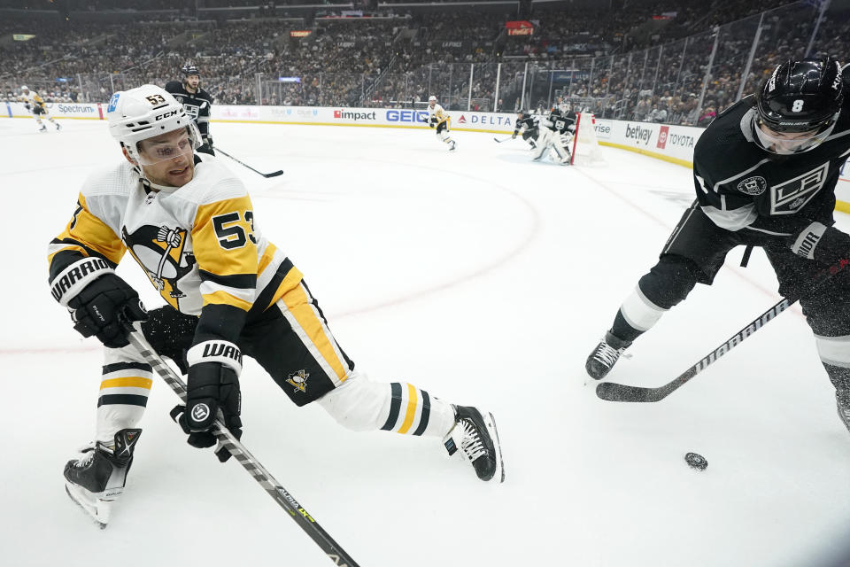 Pittsburgh Penguins center Teddy Blueger, left, falls as he vies for the puck with Los Angeles Kings defenseman Drew Doughty during the first period of an NHL hockey game Saturday, Feb. 11, 2023, in Los Angeles. (AP Photo/Mark J. Terrill)