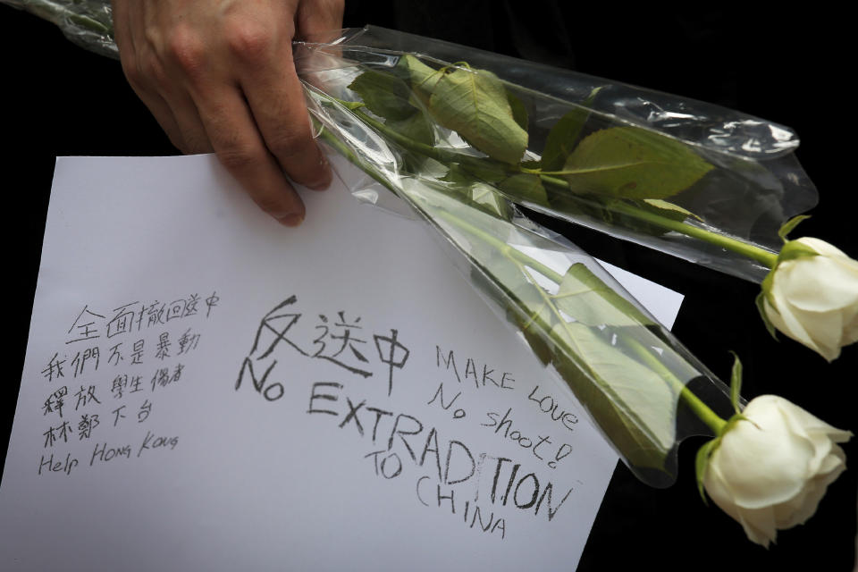 In this Sunday, June 16, 2019, photo, a protester holds flowers and a paper while marching with tens of thousands of protesters on the main road near the Legislative Council to protest against the unpopular extradition bill in Hong Kong. The various pro-democracy groups that helped drive and organize the protests are pushing for Lam’s resignation and the permanent scrapping of what they call the “evil” extradition bill. (AP Photo/Kin Cheung)