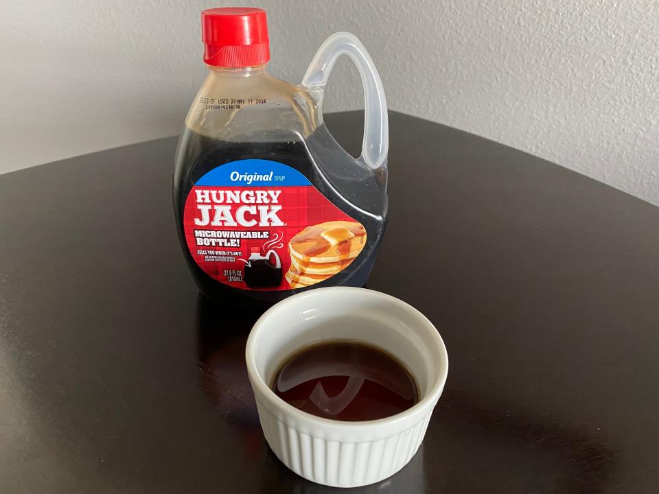 bottle of hungry jack pancake syrup next to a white ramekin filled with the syrup