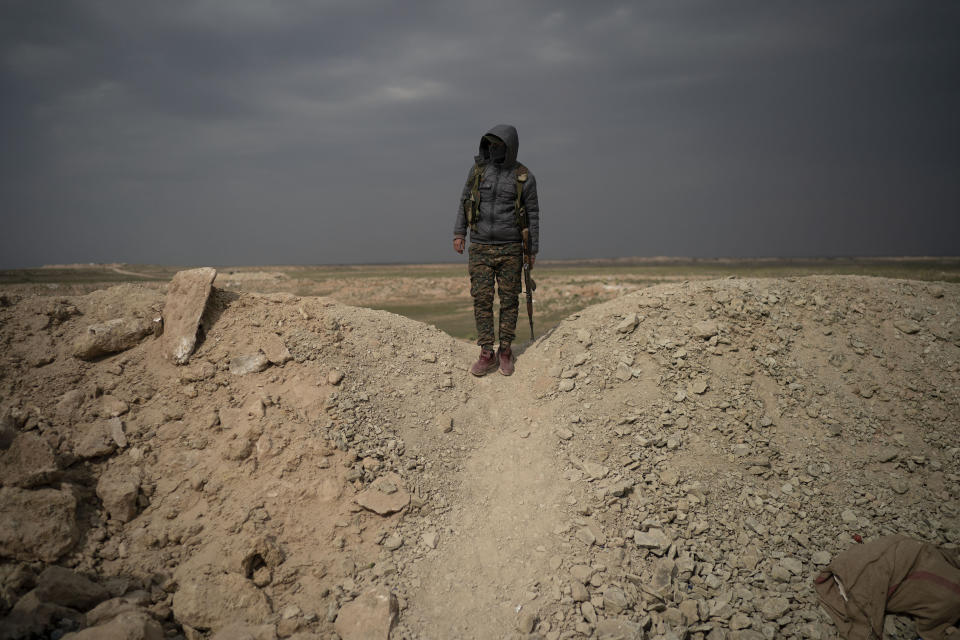 A U.S.-backed Syrian Democratic Forces (SDF) fighter stands atop a hill in the desert outside the village of Baghouz, Syria, Thursday, Feb. 14, 2019. U.S.-backed Syrian forces are clearing two villages in eastern Syria of remaining Islamic State militants who are hiding among the local population, and detaining others attempting to flee with the civilians, the U.S.-led coalition said Thursday. (AP Photo/Felipe Dana)