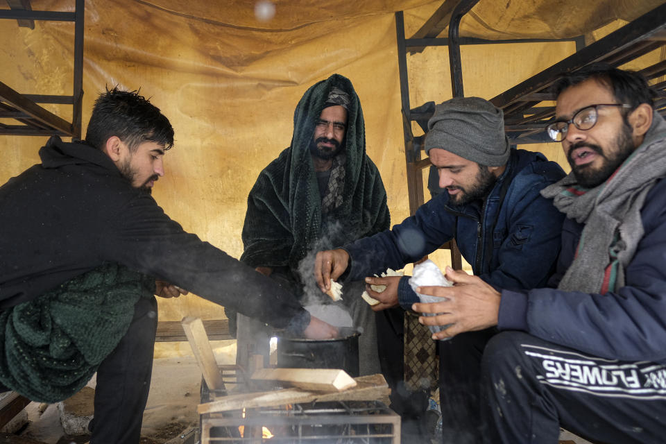 Migrants eat, at the Lipa camp, outside Bihac, Bosnia, Monday, Jan. 11, 2021. Aid workers say migrants staying at a camp in northwestern Bosnia have complained or respiratory and skin diseases after spending days in make-shift tents and containers amid freezing weather and snow blizzards. Most of the hundreds of migrants at the Lipa facility near Bosnia's border with Croatia on Monday have been accommodated in heated military tents following days of uncertainty after a fire gutted most of the camp on Dec. 23. (AP Photo/Kemal Softic)