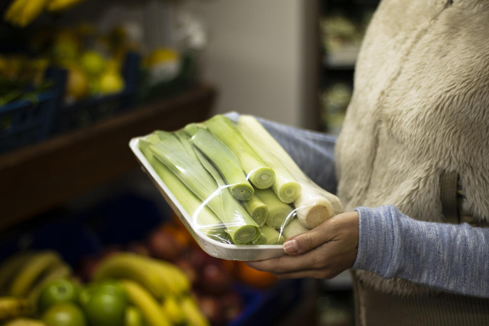 A person holding a package of leeks