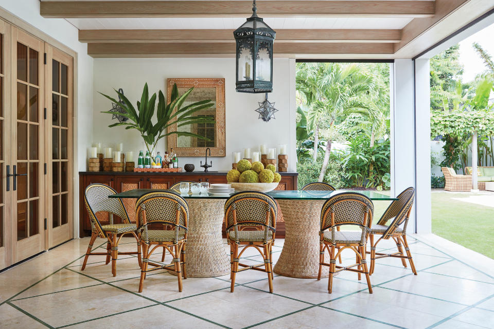 <p>For the spacious loggia, which overlooks the pool, Sharpe chose finishes to create a seamless transition between indoors and outdoors. The painted cypress decking and pickled beams run from the family room through the doors to the loggia. The pale Jerusalem stone floor features a green tile inlay, mimicking grass inlays typical of Palm Beach. “I had a magazine clipping of something similar that I’d been holding onto for years, and finally got to use this trick,” Sharpe says. The bases of the table are hand-carved teak, designed by Sharpe, and the chairs are custom designed in off-white and black by <a href="http://glacseat.com/" rel="nofollow noopener" target="_blank" data-ylk="slk:Glac Seat;elm:context_link;itc:0;sec:content-canvas" class="link ">Glac Seat</a>.</p>