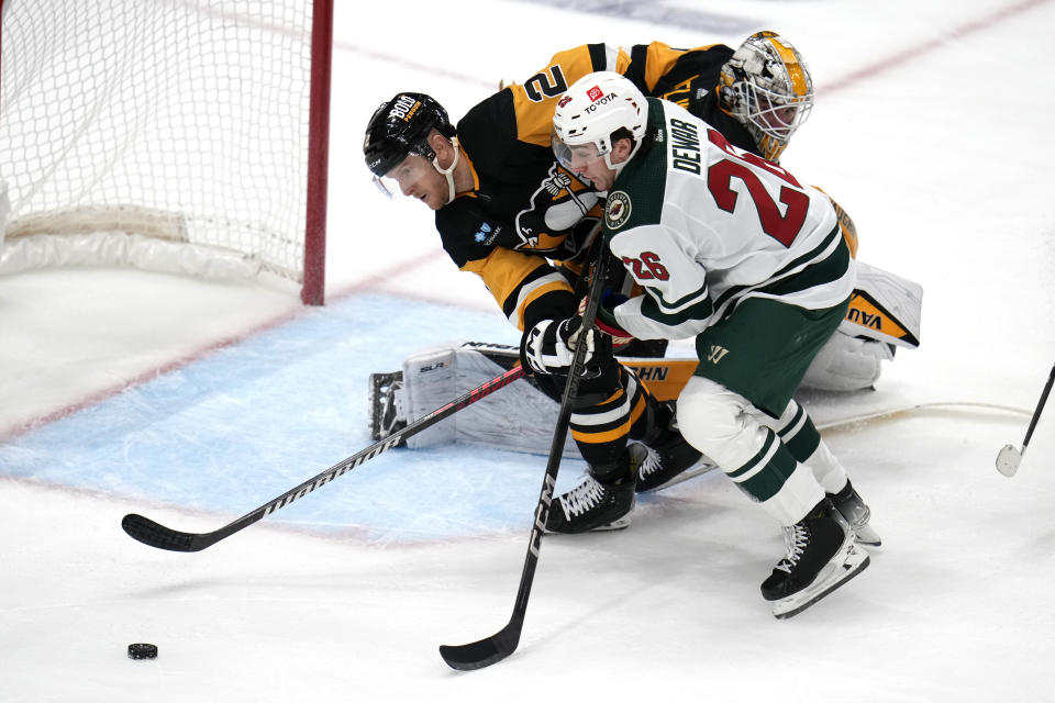 Minnesota Wild's Connor Dewar (26) cannot get off a shot in front of Pittsburgh Penguins goaltender Alex Nedeljkovic, top right, with Penguins' Chad Ruhwedel (2) defending during the first period of an NHL hockey game in Pittsburgh, Monday, Dec. 18, 2023. (AP Photo/Gene J. Puskar)