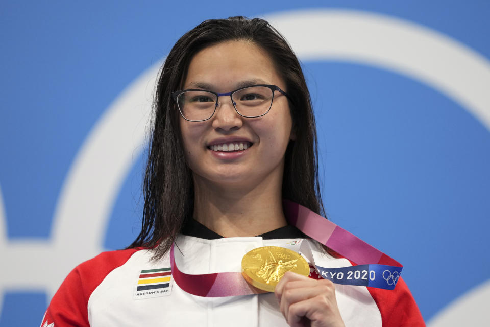 Margaret MacNeil of Canada celebrates on the podium after winning the women's 100-meter butterfly final at the 2020 Summer Olympics, Monday, July 26, 2021, in Tokyo, Japan. (AP Photo/Matthias Schrader)