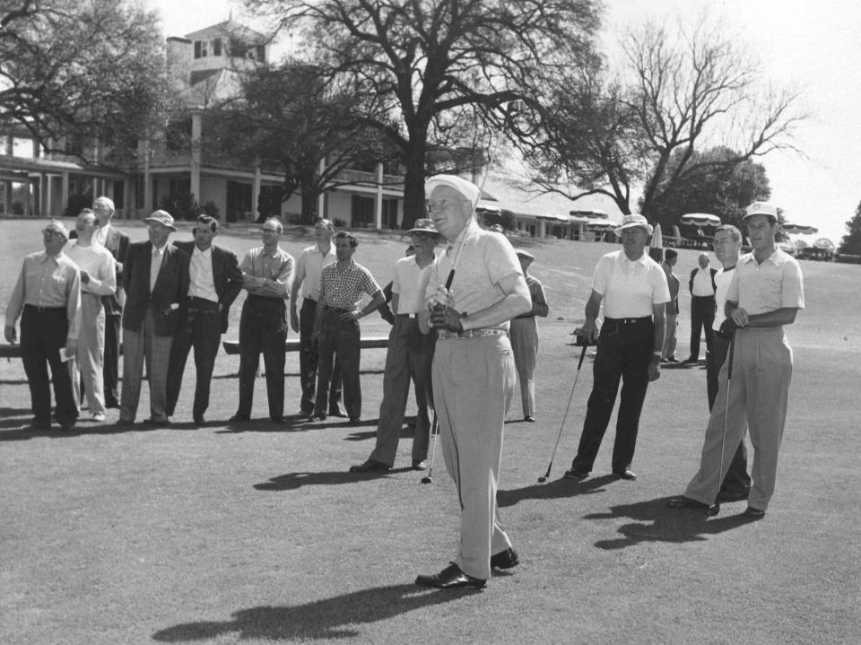 In this photo from the 1950s, President Dwight D. Eisenhower tees off in front of the clubhouse of Augusta National Golf Club.