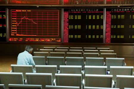 A man sits in front of a board showing market information at a securities brokerage house in Beijing