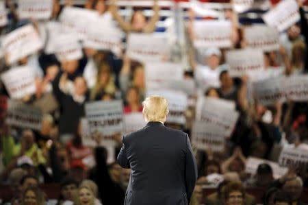 U.S. Republican presidential candidate Donald Trump watches supporters raise signs as they cheer at a campaign rally at the Iowa State Fairgrounds in Des Moines, Iowa, December 11, 2015. REUTERS/Scott Morgan