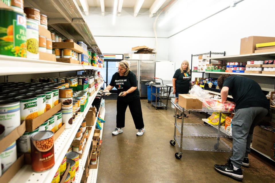 IMPACT Volunteer Coordinator Kim Coulter, left, helps volunteers sort canned food at IMPACT food pantry in the Drake neighborhood on Tuesday, August 1, 2023 in Des Moines.