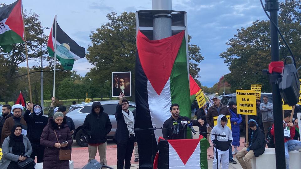 Al Quds Committee Detroit held a rally on Oct. 13, 2023, at the Henry Ford Centennial Library in Dearborn, Michigan. Tarek Bazzi is speaking at the podium. A man behind him holds a photo of the late Ayatollah Khomeini. The same group held a protest on April 5, 2024, during which some chanted "Death to America" in Arabic while Bazzi was at the podium.