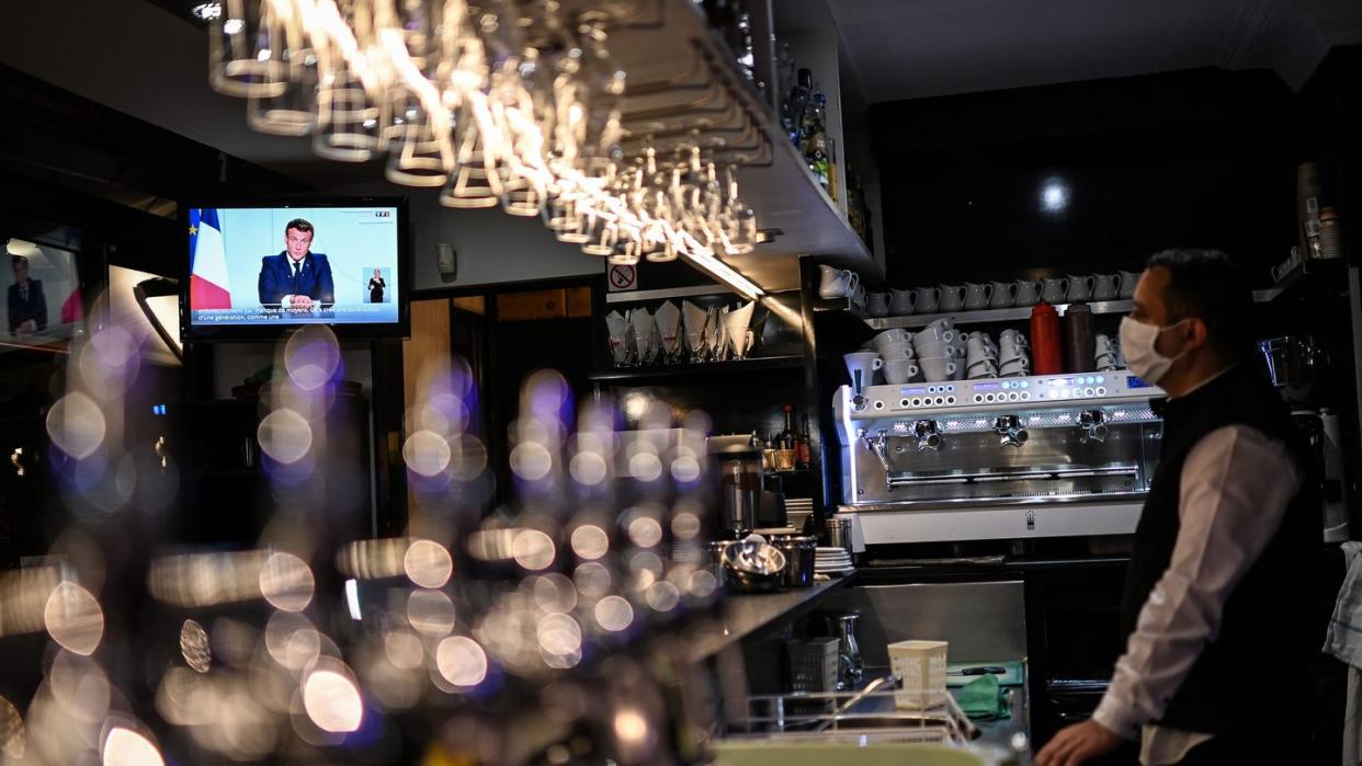 Ein Barkeeper schaut sich die Fernsehansprache von Präsident Macron in einem Café in Marseille an.