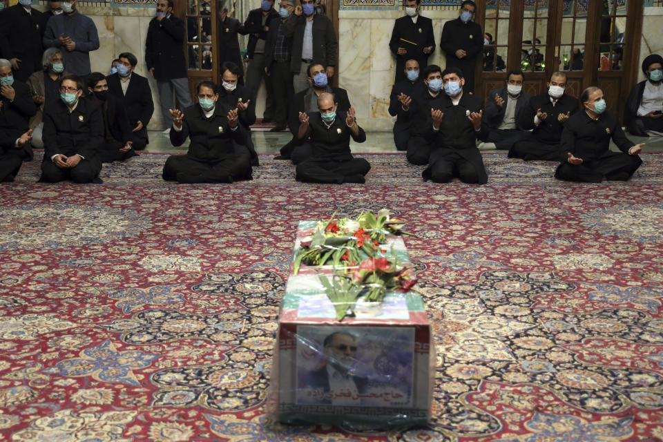 In this picture released by the Iranian Defense Ministry and taken on Saturday, Nov. 28, 2020, people pray over the flag draped coffin of Mohsen Fakhrizadeh, an Iranian scientist linked to the country's disbanded military nuclear program, who was killed on Friday, during a funeral ceremony at the Imam Reza holy shrine in the northeastern city of Mashhad, Iran. An opinion piece published by a hard-line Iranian newspaper has suggested that Iran must attack the Israeli port city of Haifa if Israel carried out the killing of a scientist. (Iranian Defense Ministry via AP)