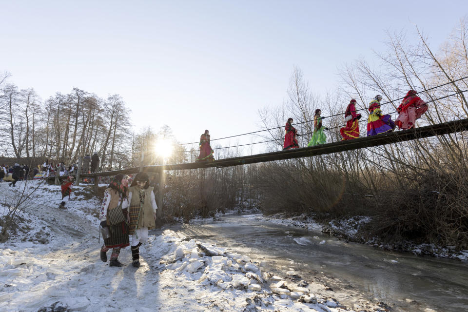 Participants, dressed in traditional costumes, cross a bridge while celebrating the Malanka festival in the village of Krasnoilsk, Ukraine, Friday, Jan. 14, 2022. Dressed as goats, bears, oxen and cranes, many Ukrainians rang in the new year last week in the colorful rituals of the Malanka holiday. Malanka, which draws on pagan folk tales, marks the new year according to the Julian calendar, meaning it falls on Jan. 13-14. In the festivities, celebrants go from house to house, where the dwellers offer them food. (AP Photo/Ethan Swope)