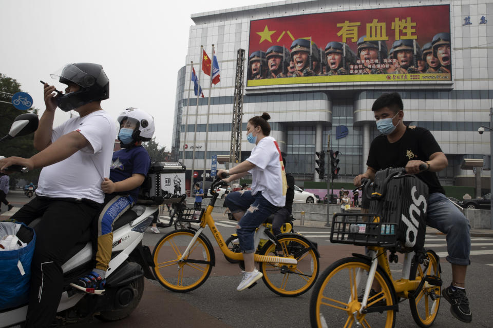 Residents ride past Chinese military propaganda with the slogan "Heroic" in Beijing on Wednesday, Aug. 26, 2020. China’s military test-fired two missiles into the South China Sea, including a “carrier killer” military analysts suggest might have been developed to attack U.S. forces, a newspaper reported Thursday, Aug. 27, 2020. (AP Photo/Ng Han Guan)