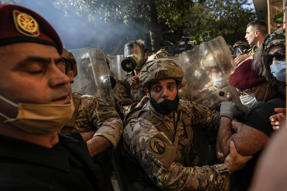 Lebanese army soldiers scuffle with retired members of the Lebanese security forces and other protesters after they removed a barbed-wire barrier in order to advance towards government buildings during a protest in Beirut, Lebanon, Tuesday, April 18, 2023. Earlier in the day, Lebanon's Parliament voted to postpone municipal elections in the crisis-stricken country that had been planned for May 2023 by up to a year. (AP Photo/Hassan Ammar)