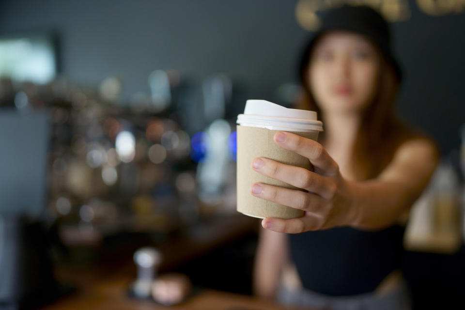 A barista holding out a coffee