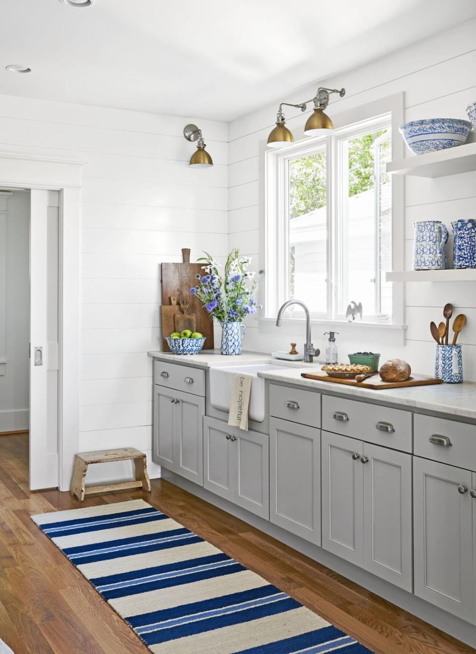 a small farmhouse kitchen with gray cabinets and white shiplap walls and blue and white accents