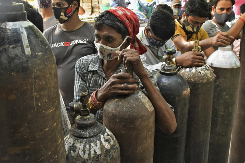 FILE - In this May 8, 2021, file photo, Indians wait to refill oxygen cylinders for COVID-19 patients at a gas supplier facility in New Delhi, India. The capital of New Delhi is seeing some improvement in the fight against the coronavirus, but experts say the crisis is far from over in the country of nearly 1.4 billion people. Hospitals are still overwhelmed and officials are struggling with short supplies of oxygen and beds. (AP Photo/Ishant Chauhan, File)