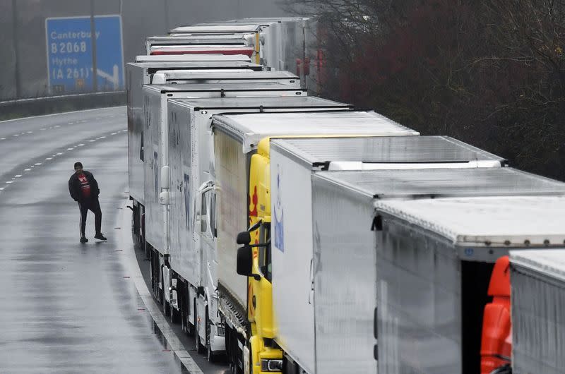 A driver walks next to lorries parked on the M20 motorway towards Eurotunnel and the Port of Dover