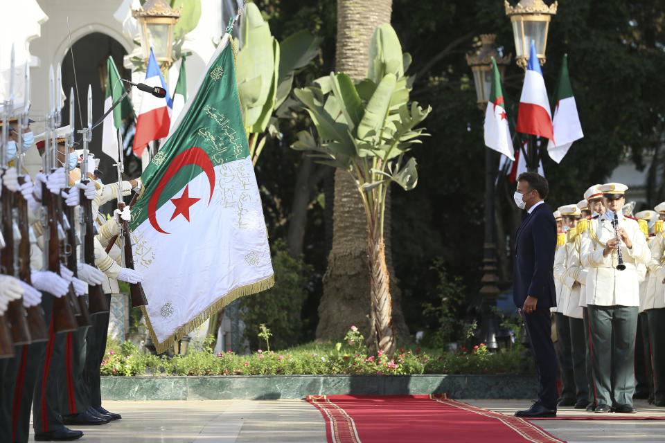 French President Emmanuel Macron, right, reviews the troops before his talks with Algerian President Abdelmajid Tebboune, Thursday, Aug. 25, 2022 in Algiers. French President Emmanuel Macron is in Algeria for a three-day official visit aimed at addressing two major challenges: boosting future economic relations while seeking to heal wounds inherited from the colonial era, 60 years after the North African country won its independence from France. (AP Photo/Anis Belghoul)