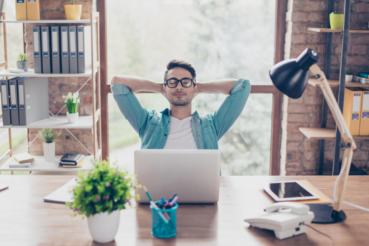 Portrait of smiling smart freelancer in casual clothes and spectacles enjoying his work at home