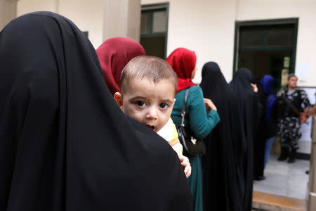 A woman holds her baby as she waits her turn to vote at a polling station during the parliamentary election, in Beirut, Lebanon, May 6, 2018. REUTERS/Mohamed Azakir