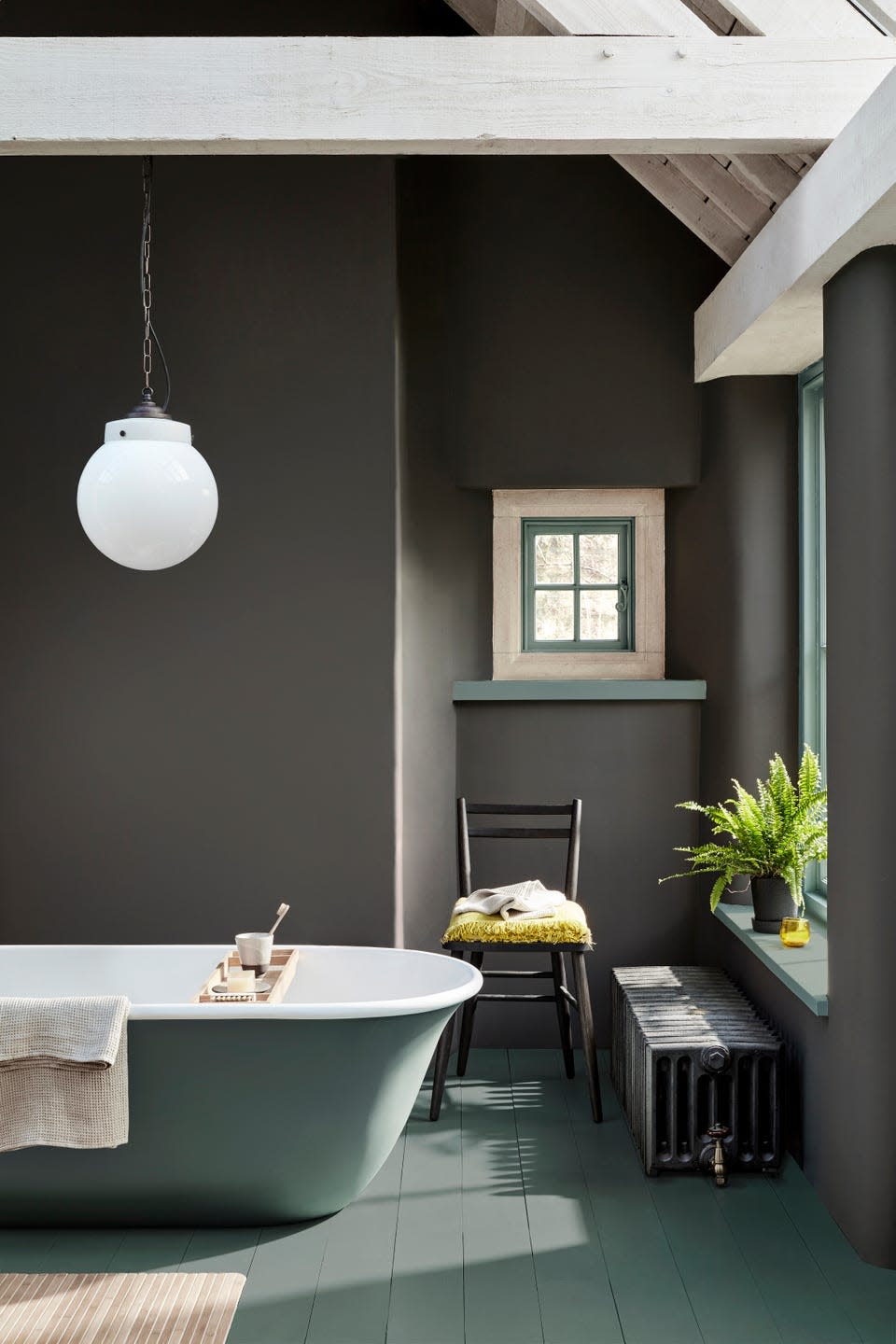 Bathroom with brown painted walls, a grey freestanding bathtub and a spherical pendant light