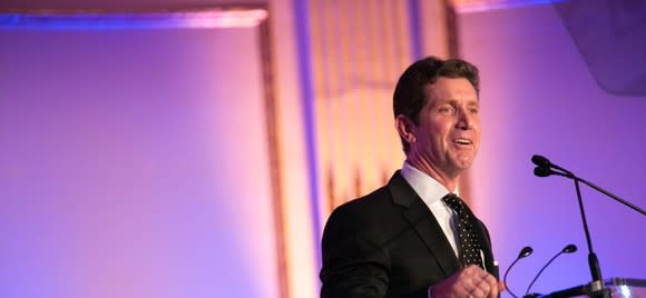 Johnson & Johnson CEO Alex Gorsky standing at a stage in front of a purplish backdrop.