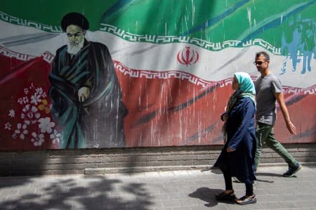 People walk in front of a mural of Iran's late leader Ayatollah Ruhollah Khomeini in Tehran