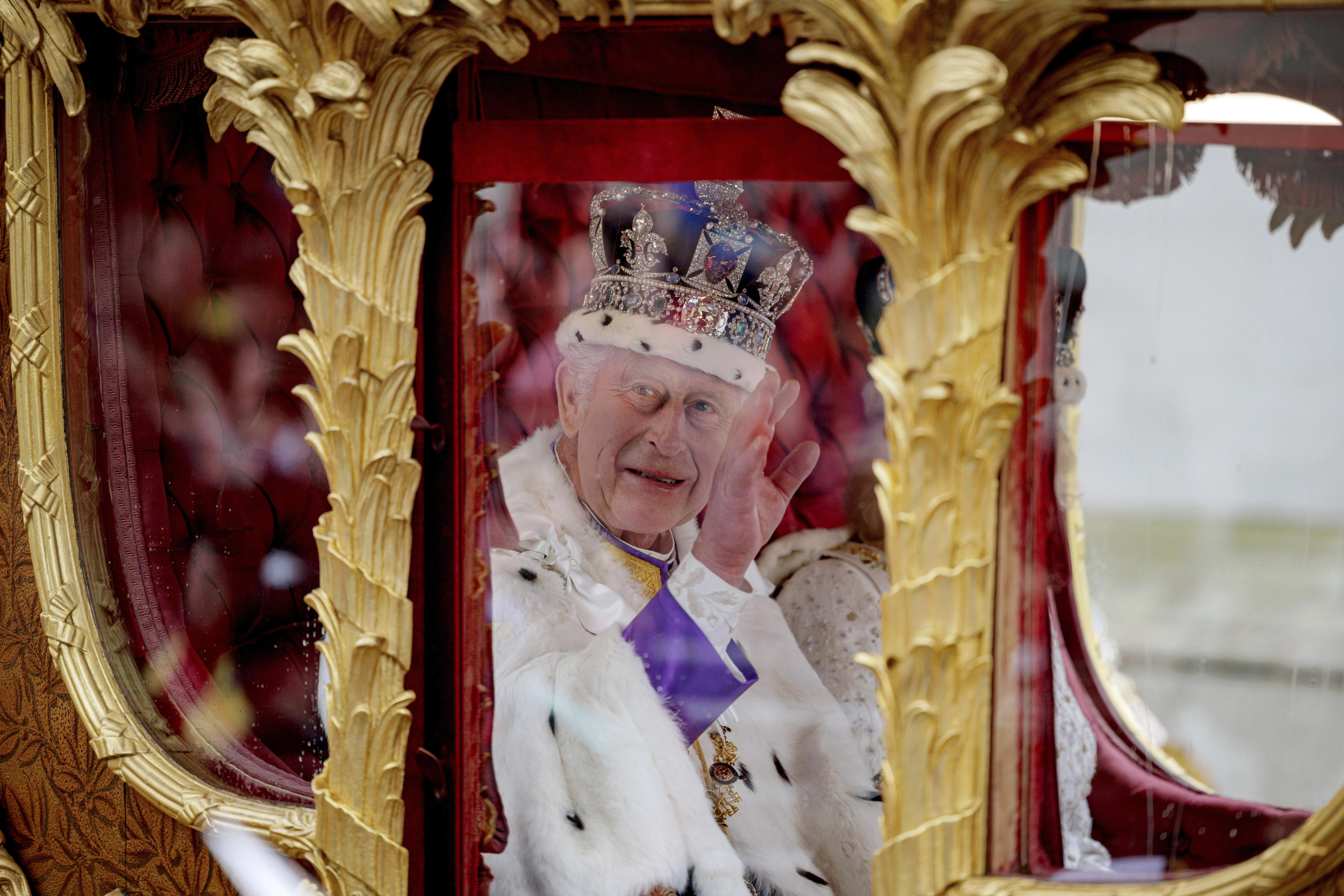 Britain's King Charles III greets the crowd as he and Queen Camilla travel to Buckingham Palace after the coronation ceremony at Westminster Abbey in London in May 2023. 